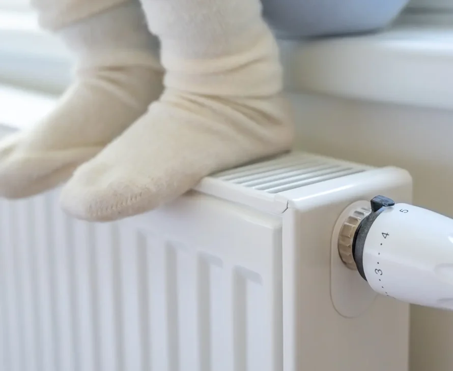 Warm radiator with feet resting on it after successful boiler service